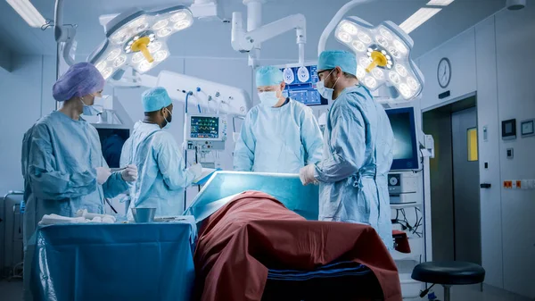 전문 외과의사의 Diverse Team of Professional Surgeons Performing Inusual Surgery on the Hospital Operating Room. 간호사는 외과의사, 마취과 의사, 모니터 바이탈에게 기기를 나눠 준다. 현대의 병원 — 스톡 사진