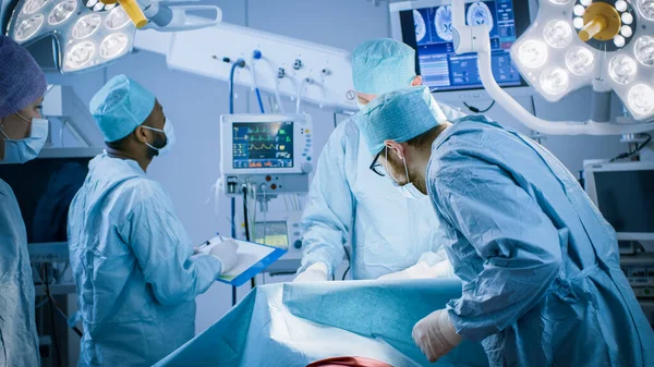 Διαφορετική ομάδα επαγγελματιών χειρουργών, βοηθών και νοσηλευτών που πραγματοποιούν επεμβατική χειρουργική σε ασθενή στο χειρουργείο του Νοσοκομείου. Πραγματικό σύγχρονο νοσοκομείο με αυθεντικό εξοπλισμό. — Φωτογραφία Αρχείου