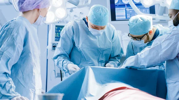 Vielfältiges Team aus professionellen Chirurgen, Assistenten und Krankenschwestern, die invasive Operationen an einem Patienten im Operationssaal des Krankenhauses durchführen. Echt modernes Krankenhaus mit authentischer Ausstattung. — Stockfoto