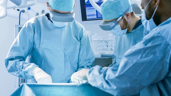 Chirurgen, die eine Augmented-Reality-Brille tragen, führen im High-Tech-Krankenhaus Mixed-Reality-Operationen auf dem neuesten Stand der Technik durch. Ärzte und Assistenten arbeiten im Operationssaal. — Stockfoto
