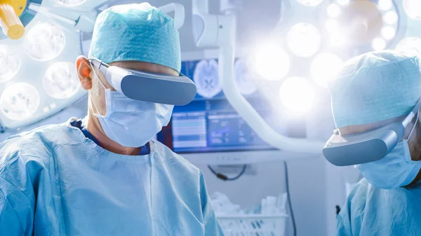 Surgeons in Augmented Reality Glasses Perform State of the Art Surgery in High Tech Hospital. Doctors and Assistants Working in Operating Room.