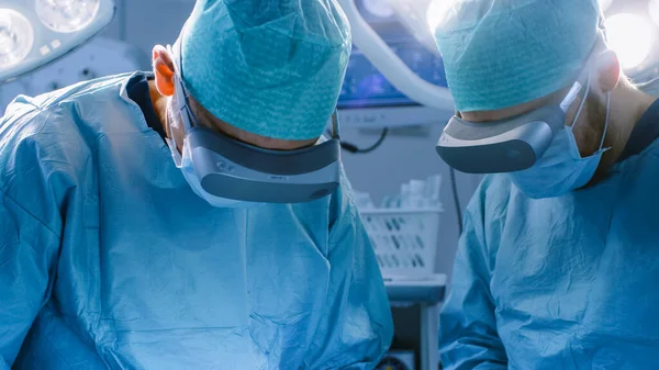 Cirujanos en gafas de realidad aumentada realizan cirugía de última generación en un hospital de alta tecnología. Médicos y asistentes que trabajan en quirófano. — Foto de Stock