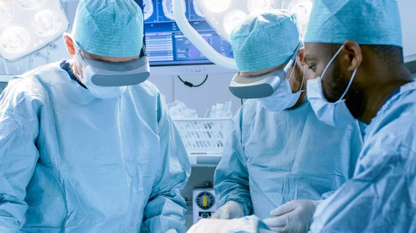 증강현실 안경을 사용하는 외과 의사들은 첨단 기술 병원에서 예술 수술의 상태를 조성 한다. 수술 실에서 일하는 의사들과 석면. — 스톡 사진