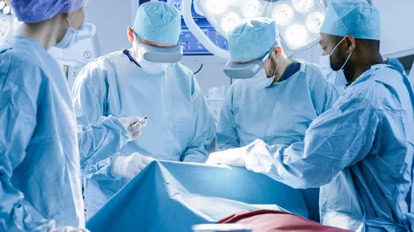 Хірурги носять окуляри віртуальної реальності для виконання стану художньої хірургії в технологічно передовій лікарні. Лікарі та асистенти працюють в операційній . — стокове фото