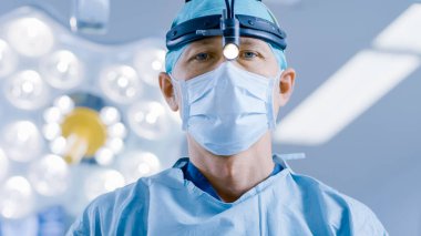 Hastane ameliyathanesinde cerrahi fenerli profesyonel cerrah kameraya bakıyor.. 