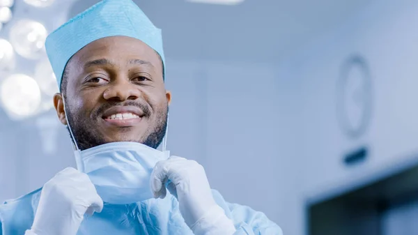 Retrato del cirujano profesional se quita la máscara quirúrgica después de una operación exitosa. En el fondo Moderno quirófano del hospital. —  Fotos de Stock