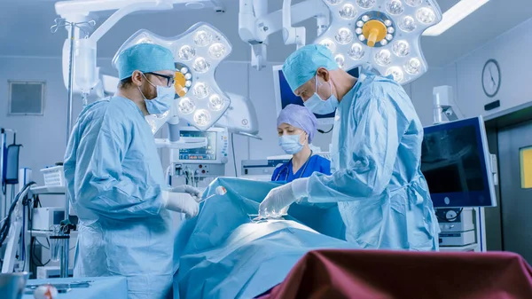 Im Operationssaal des Krankenhauses: Vielfältiges Team aus professionellen Chirurgen und Krankenschwestern vernäht Wunde nach erfolgreicher Operation. — Stockfoto