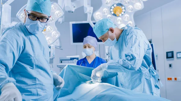 En el quirófano del hospital Equipo Diverso de Cirujanos Profesionales y Enfermeras Sutura Herida después de una Cirugía Exitosa. Cirujano tomar instrumento quirúrgico. —  Fotos de Stock