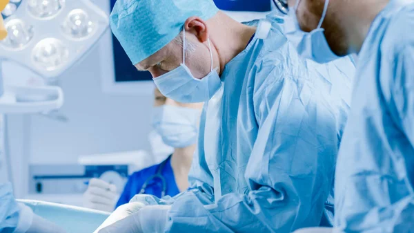 Im Operationssaal des Krankenhauses: Vielfältiges Team aus professionellen Chirurgen und Krankenschwestern vernäht Wunde nach erfolgreicher Operation. — Stockfoto