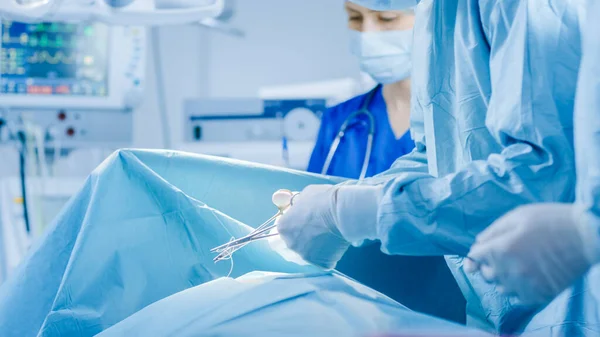 Im Operationssaal des Krankenhauses: Vielfältiges Team aus professionellen Chirurgen und Krankenschwestern vernäht Wunde nach erfolgreicher Operation. — Stockfoto