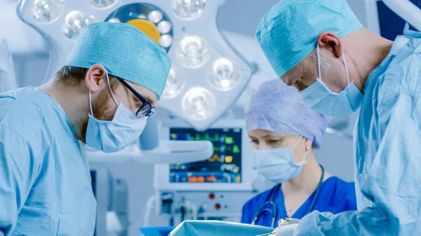 Im Operationssaal des Krankenhauses: Vielfältiges Team aus professionellen Chirurgen und Krankenschwestern vernäht Wunde nach erfolgreicher Operation. — Stockfoto
