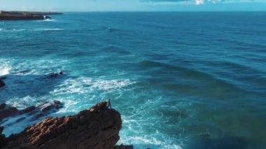 Hava Aracı Görüntüsü: Güzel Okyanus Manzaralı Portekiz Rocky Shore. Portekiz üzerinde uçmak, Oceanic Waves 'le sahil şeridi yuvarlanmak, uçurumlara çarpmak. Yalnız Balıkçı Balık Tutuyor. Praia Do Guincho