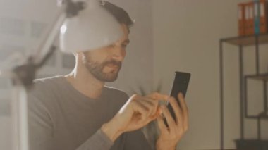 Dahili Ofis Stüdyosunda oturan Profesyonel Yaratıcı Adam Akıllı Telefon Kullanan Adam, Cep Telefonu Kullanan Adam, İnternet Aracı, Sosyal Ağ Medyası. 360 Derece İzleme Yayı Görüntüsü