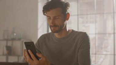 Dahili Ofis Stüdyosunda oturan Profesyonel Yaratıcı Adam Akıllı Telefon, Telefon, İnternet, Sosyal Ağ Medya 'da geziniyor. 360 Derece İzleme Aracı Atışı. Kamera Hareket Ediyor