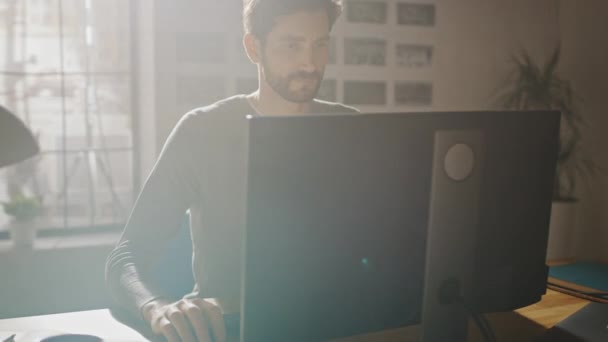 Diseñador creativo sentado en su escritorio en Office Studio Trabajando en una computadora de escritorio con aplicación de desarrollo de software para teléfonos inteligentes en pantalla. Web, Desarrollador de aplicaciones. Tiro de arco de seguimiento de 360 grados — Vídeo de stock