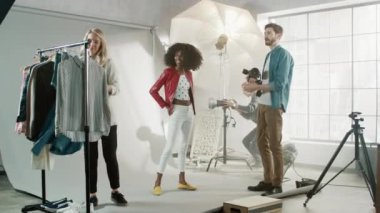 Fotoğraf çekiminin kulisinde stilist, Güzel Siyah Manken Kız için Kıyafet ve Kıyafet Seçiyor, Fotoğrafçı Çekime Hazır. Profesyonel Moda Stüdyosu Fotoğrafçılığı