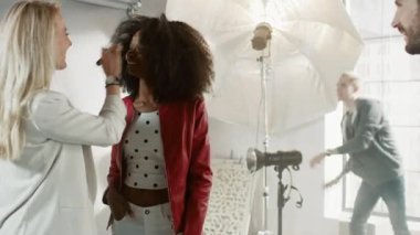 Fotoğraf çekiminin kulisinde: Makyöz, Güzel Siyah Modele Makyaj Uygular, Profesyonel Kamerayla Fotoğraf Çekmeye Başlar. Moda Dergisi Stüdyo Fotoğrafları