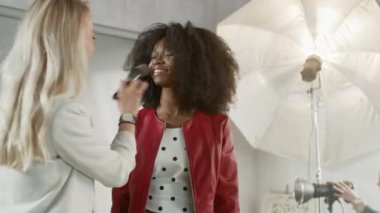 Fotoğraf çekiminin kulisinde: Makyöz, Güzel Siyah Modele Makyaj Uygular, Profesyonel Kamerayla Fotoğraf Çekmeye Başlar. Moda Dergisi Stüdyo Fotoğrafları