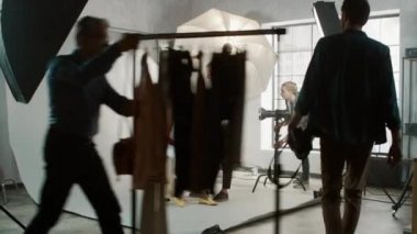 Fotoğraf çekiminin sahne arkası: Makyöz, gür kıvırcık saçlı güzel siyah modele ruj sürüyor. Fotoğrafçı fotoğraf çekmeye hazır. Moda Dergisi Stüdyo Fotoğrafları