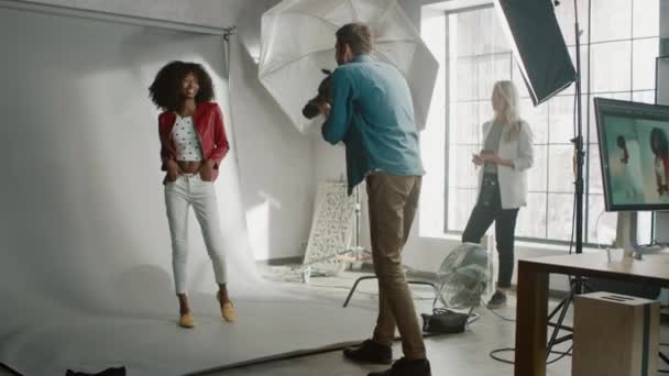 Modelo preto bonito posando para um fotógrafo, ele tira fotos com câmera profissional. Elegante Photoshoot Revista de Moda feito com Pro Equipment em um estúdio. Zoom modelo em tiro — Vídeo de Stock