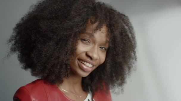 Menina preta atraente com cabelo encaracolado exuberante posando para uma fotografia de revista de moda. Menina bonita sorri Brincalhamente, Atos e Brinca com expressões faciais. Fotografia feita em estúdio profissional — Vídeo de Stock