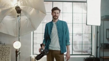 Profesyonel Ekipmanlı Fotoğraf Stüdyosunda: Yakışıklı Fotoğrafçı Holding State of the Art Camera Arka planda Softbox Aydınlatma ile Fotoğraf Çekmeye Hazır