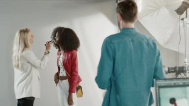 Fotoğraf çekiminin kulisinde: Makyöz, Güzel Siyah Modele Makyaj Uygular, Profesyonel Kamerayla Fotoğraf Çekmeye Başlar. Moda Dergisi Stüdyo Fotoğrafları