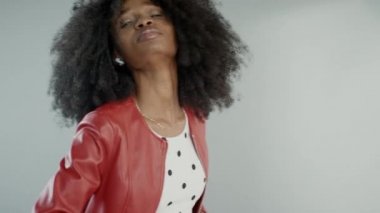 Moda dergisi için kıvırcık saçlı çekici siyah kız pozu veren bir fotoğrafçı. Güzel Kız Neşeli Gülümser, Dans eder ve Yüz İfadeleriyle Oynar. Stüdyoda fotoğraf çekimi. Orta Çekim