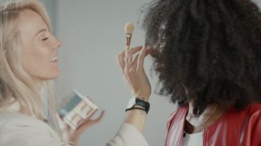 Fotoğraf çekiminin sahne arkası: Makyöz Güzel Siyah Modele Makyaj Yapıyor. Moda Dergisi Stüdyo Fotoğrafları
