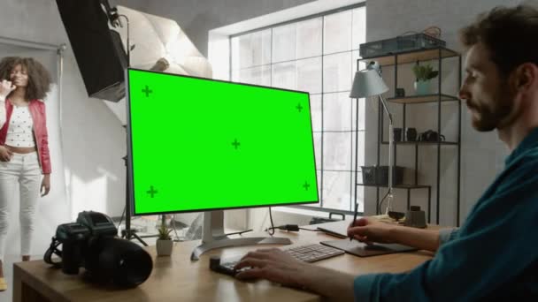 За лаштунками фотосесії: візажист застосовує макіяж до красивої чорної дівчини. Фоторедактор працює на настільному комп'ютері з екранним дисплеєм Green Mock-up. Журнал моди Інтернет — стокове відео