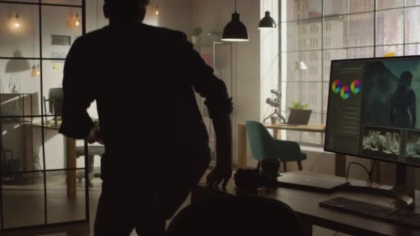 Νέος δημιουργικός άνθρωπος στέκεται από το γραφείο του με τον προσωπικό υπολογιστή και οθόνη με λογισμικό επεξεργασίας βίντεο και έρχεται στον τοίχο με οργανωμένη Storyboard στο δροσερό γραφείο Loft του. Ηλιόλουστη μέρα. — Αρχείο Βίντεο