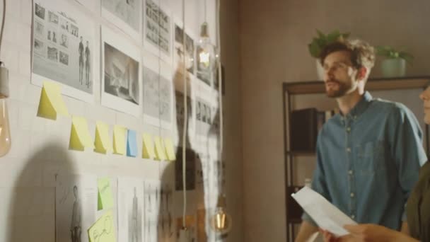 Young Creative Male en Female organiseren een Storyboard op een Wall of Their Cool Office Loft. Foto 's vertegenwoordigen Toekomstige Beweging Video. Collega 's werken en discussiëren over het project. Zonnige dag. — Stockvideo