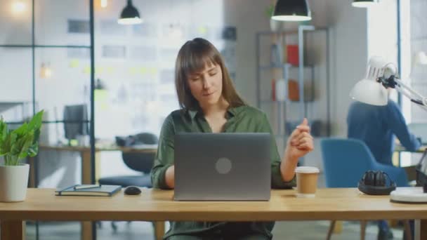 Young Beautiful Brunette Works on a Laptop Computer in Cool Creative Agency in a Loft Office. She is Happy, Smiling, Dancing and is Having Fun. — Stock Video