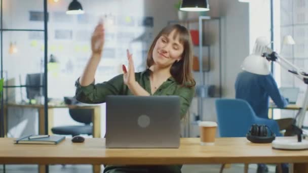 若い美しいブルネットはロフトオフィスのクールなクリエイティブエージェンシーのラップトップコンピュータで動作します。彼女は幸せです,笑顔,ダンスと楽しみを持っています. — ストック動画
