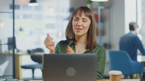 Young Beautiful Brunette werkt op een Laptop Computer in Cool Creative Agency in een Loft Office. Ze is gelukkig, glimlachend, dansend en heeft plezier. — Stockvideo