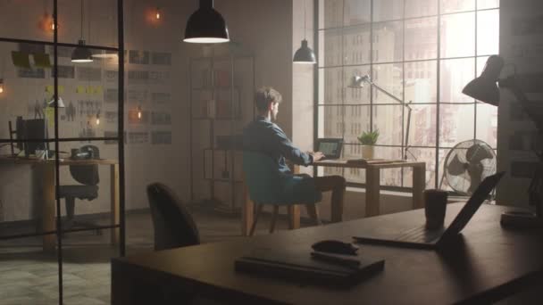 Handsome Creative Developer Works on a Laptop in His Studio. 2012 년 11 월 1 일에 확인 함 . Designing Apps and Social Media Design Structure in His Sunny Loft Office. 창문으로 본 현대 도시의 모습. — 비디오