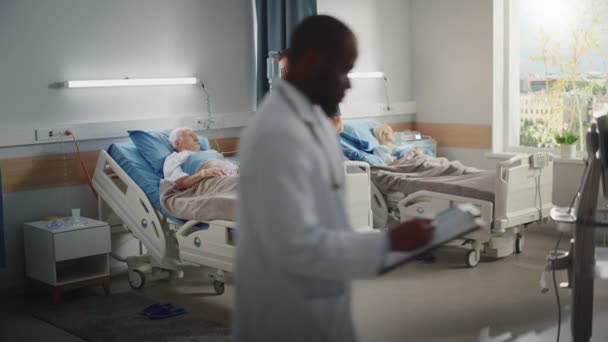 Le médecin du quartier de l'hôpital parle avec un vieux patient au lit — Video