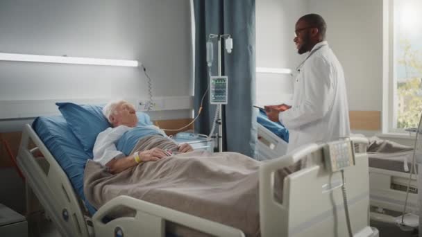 Hastane koğuşu doktoru yaşlı hastayla yatakta konuşuyor. — Stok video