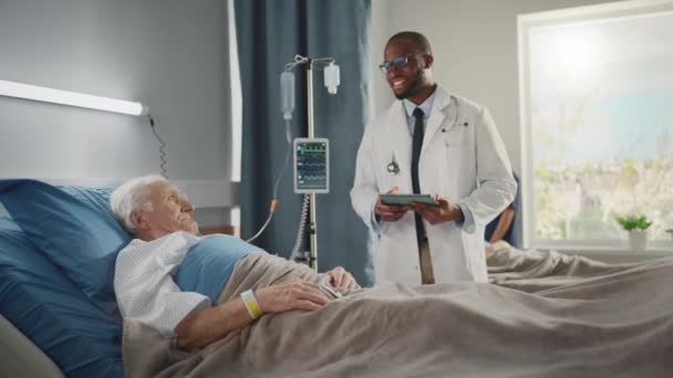 Врач отделения больницы беседует со старым пациентом в постели — стоковое видео