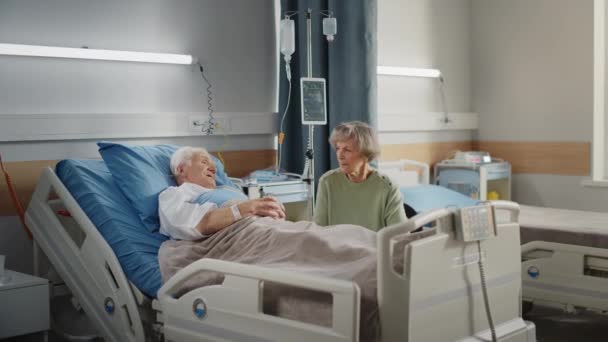 Старик в палате больницы в постели супруга посещение — стоковое видео