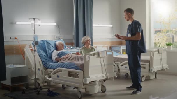 Hospital Ward Old Husband en la cama habla con su esposa visitando al doctor habla — Vídeos de Stock