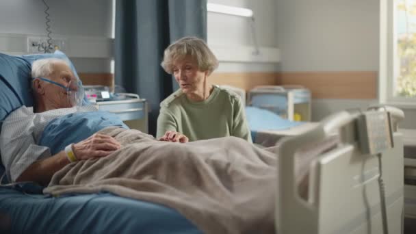 Hospital Ward Old Husband con máscara de oxígeno en la cama habla con la esposa visitando — Vídeos de Stock