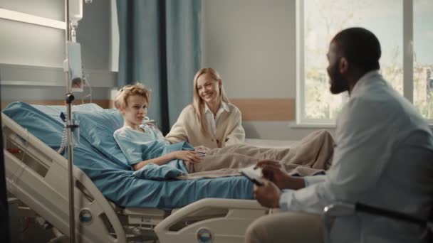 Hospital Ward Young Boy en la cama Madre Visitante Doctor Consulting — Vídeos de Stock