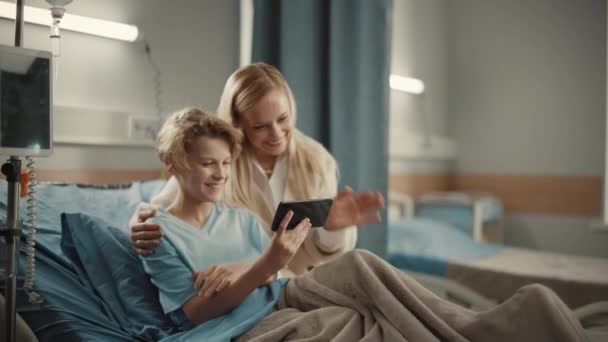 Hospital Ward Young Boy in Bed Showing Mother Smartphone — Stock Video