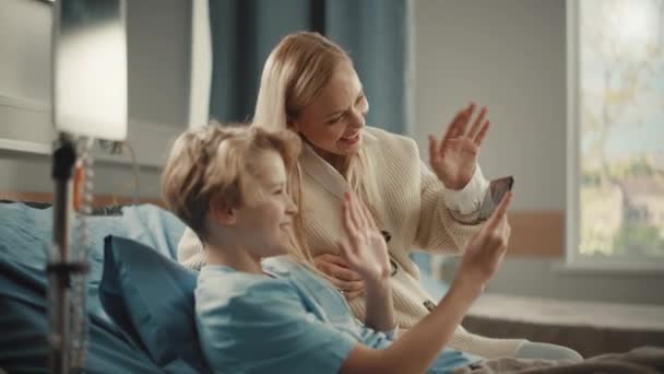 Nemocnice Oddělení Mladý chlapec v posteli ukazuje matku Smartphone — Stock video
