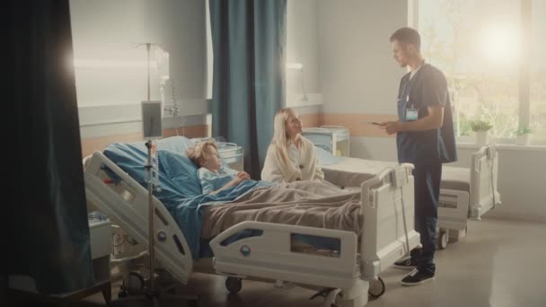 Sjukhusavdelning ung pojke i sängen mor besöker läkare konsultera — Stockvideo
