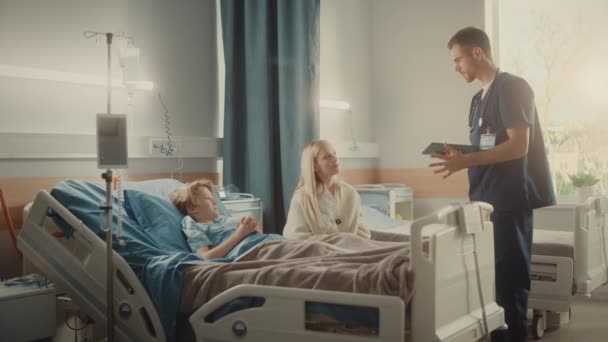 Sjukhusavdelning ung pojke i sängen mor besöker läkare konsultera — Stockvideo