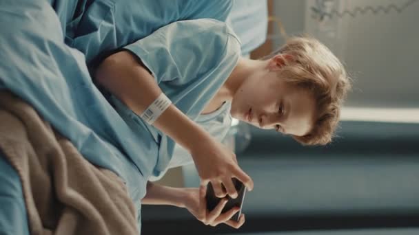Vertical Screen Hospital Ward Young Boy in Bed Using Smartphone — Stock video