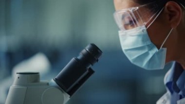 Laboratuvarda Kadın Maskeli Bilimadamını Mikroskop kullanarak Kapat