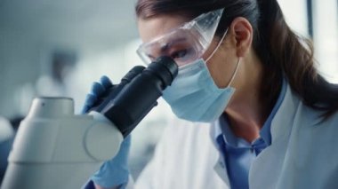 Laboratuvarda Kadın Maskeli Bilimadamını Mikroskop kullanarak Kapat